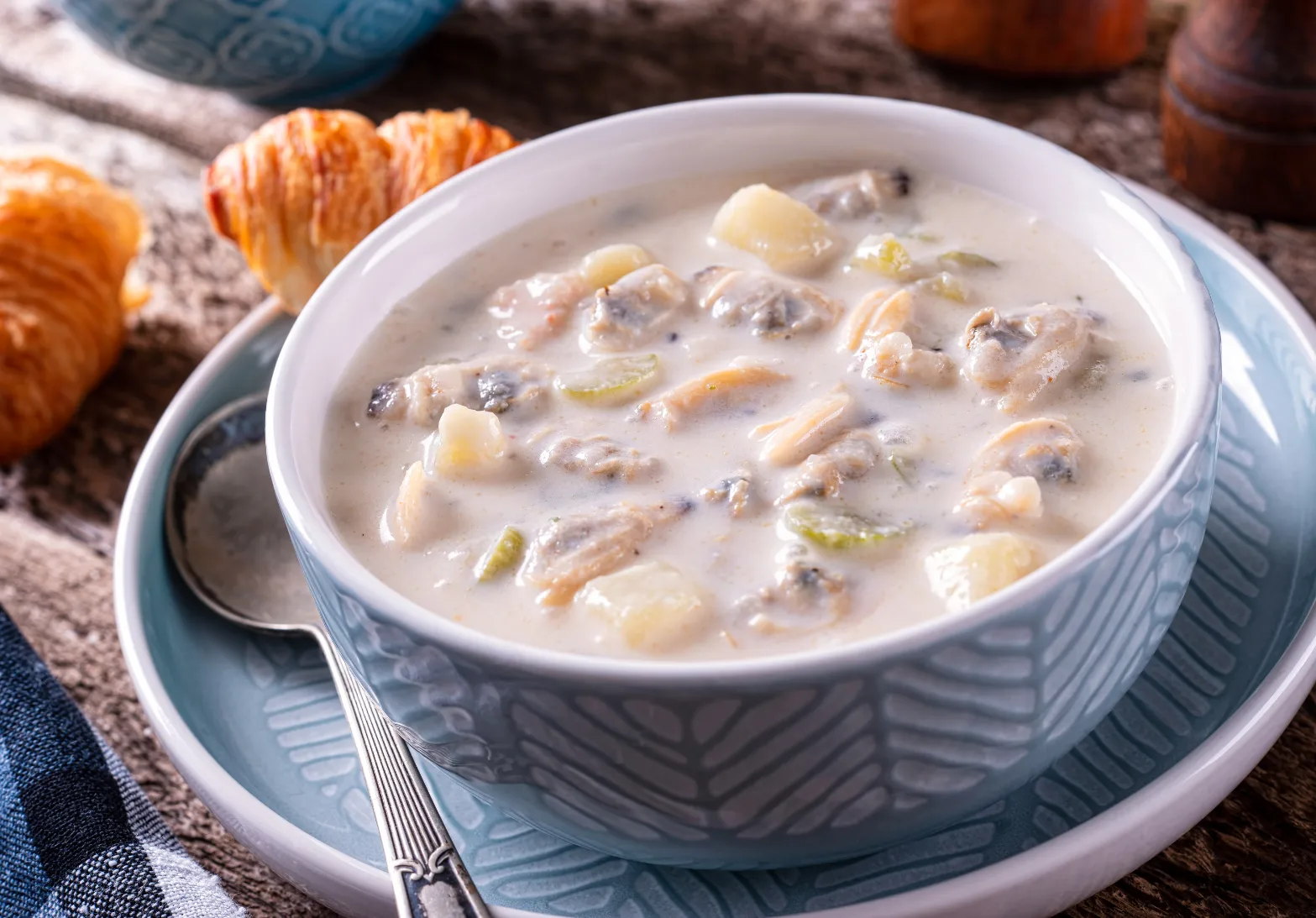 Creamy New England clam chowder with potatoes and celery served in a bowl.